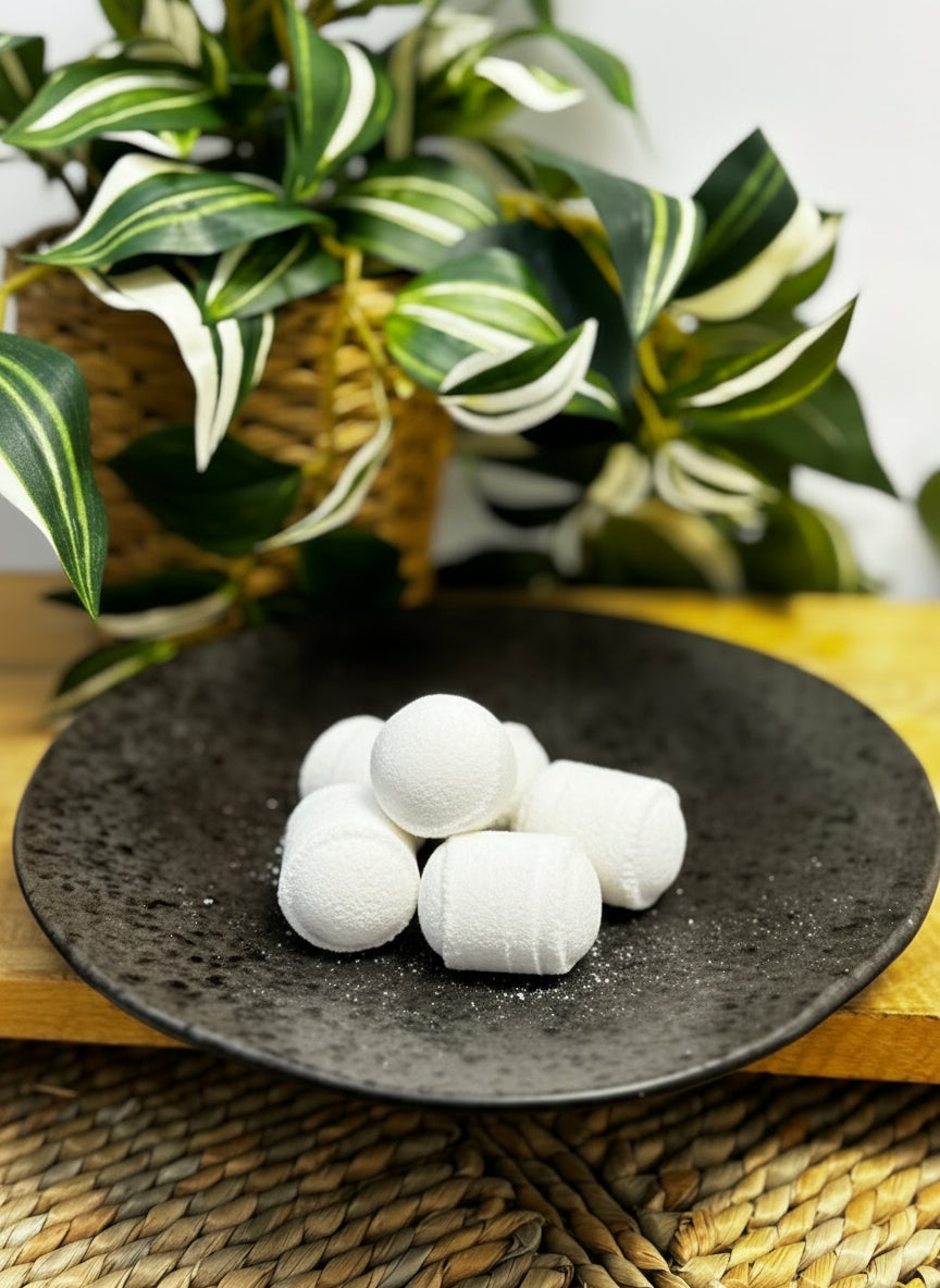 pure white mini bath bombs on a black speckled plate and a plant in the background